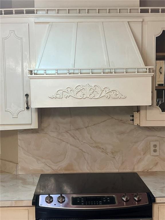 kitchen featuring stainless steel electric stove, light countertops, backsplash, and white cabinetry