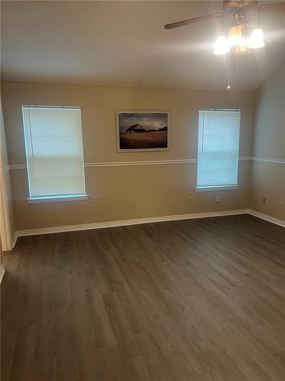 unfurnished room featuring a ceiling fan, dark wood-type flooring, and baseboards