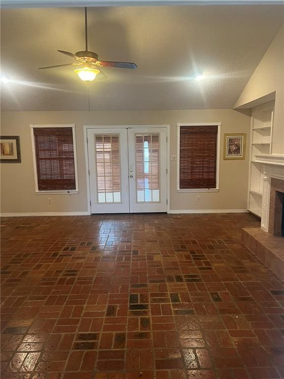 unfurnished living room with baseboards, a ceiling fan, brick floors, and a tile fireplace