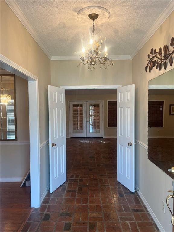 corridor with a chandelier, a textured ceiling, brick flooring, baseboards, and ornamental molding