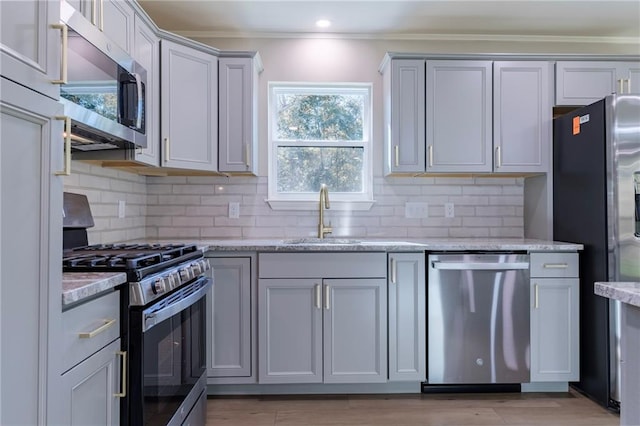 kitchen featuring crown molding, sink, light stone countertops, appliances with stainless steel finishes, and tasteful backsplash