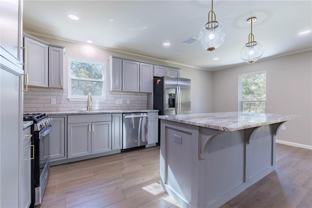 kitchen with pendant lighting, sink, appliances with stainless steel finishes, tasteful backsplash, and a kitchen island