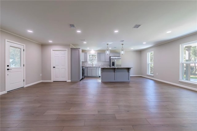 kitchen featuring gray cabinetry, a center island, hanging light fixtures, dark hardwood / wood-style floors, and stainless steel fridge