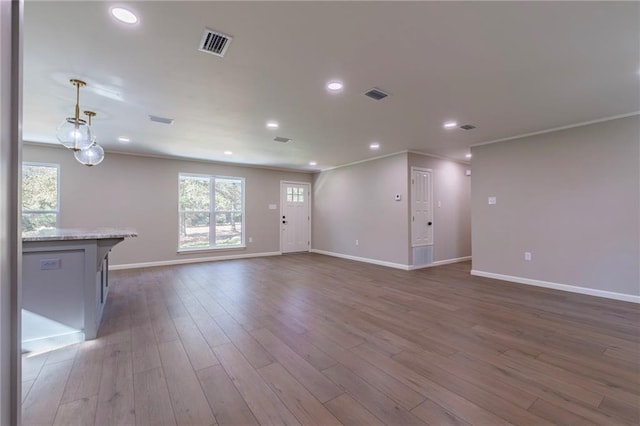 unfurnished living room featuring hardwood / wood-style floors and ornamental molding