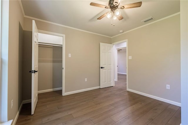 unfurnished bedroom featuring ceiling fan, light wood-type flooring, ornamental molding, and a closet