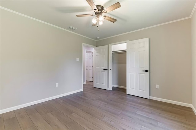 unfurnished bedroom featuring ceiling fan, light hardwood / wood-style floors, ornamental molding, and a closet