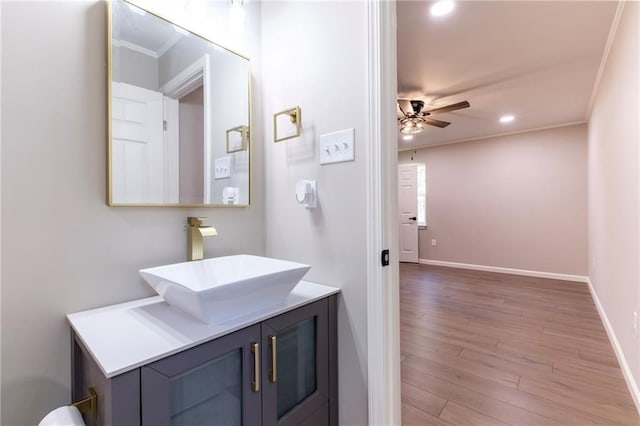 bathroom with hardwood / wood-style floors, ceiling fan, ornamental molding, and vanity