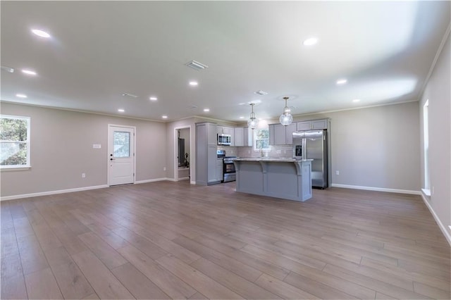 kitchen with ornamental molding, stainless steel appliances, gray cabinets, a kitchen island, and hanging light fixtures