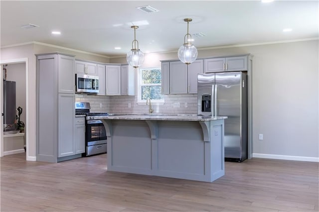 kitchen featuring light stone countertops, stainless steel appliances, pendant lighting, decorative backsplash, and a kitchen island