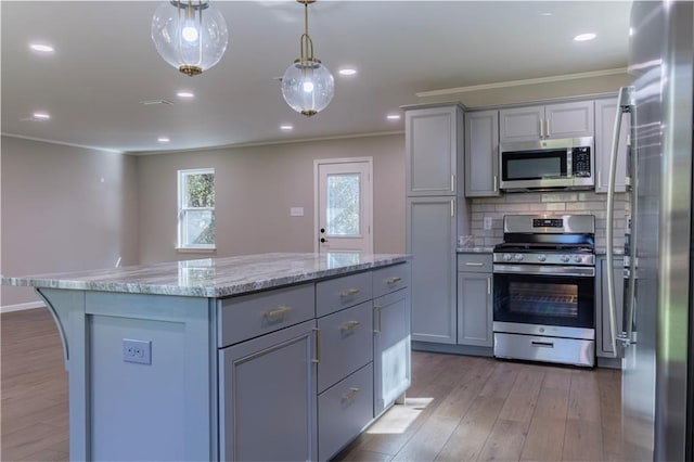 kitchen with tasteful backsplash, gray cabinetry, hanging light fixtures, and stainless steel appliances