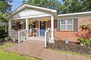 view of front of house with board and batten siding, covered porch, and brick siding
