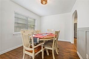 dining room featuring wood finished floors and arched walkways