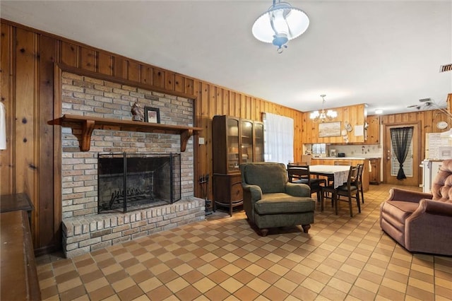 2950 Pinetucky Rd, Mobile, AL 36618 - living room featuring wooden walls, a chandelier, light tile patterned flooring, and a brick fireplace