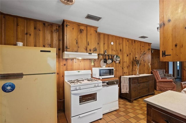 2950 Pinetucky Rd, Mobile, AL 36618 - kitchen featuring white appliances, under cabinet range hood, wood walls, brown cabinetry, and light tile patterned floors