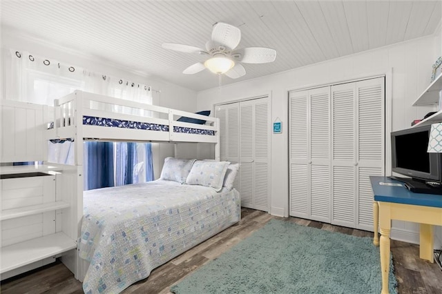 bedroom with ceiling fan, two closets, and wood finished floors