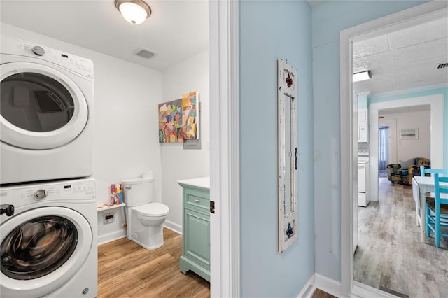 washroom featuring light wood-type flooring, baseboards, visible vents, and stacked washer and clothes dryer