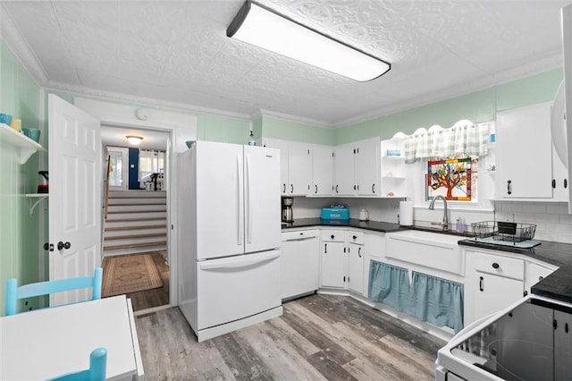 kitchen featuring white appliances, a sink, open shelves, light wood finished floors, and dark countertops