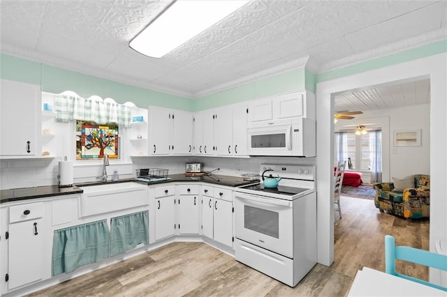 kitchen with dark countertops, white appliances, open shelves, and a sink