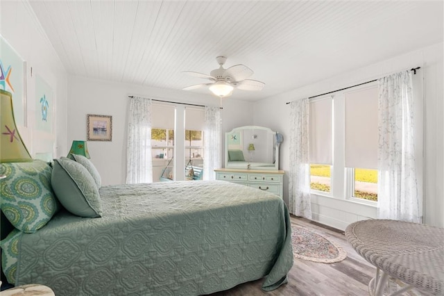 bedroom with multiple windows, ceiling fan, and wood finished floors