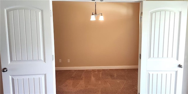 empty room featuring carpet floors and a notable chandelier