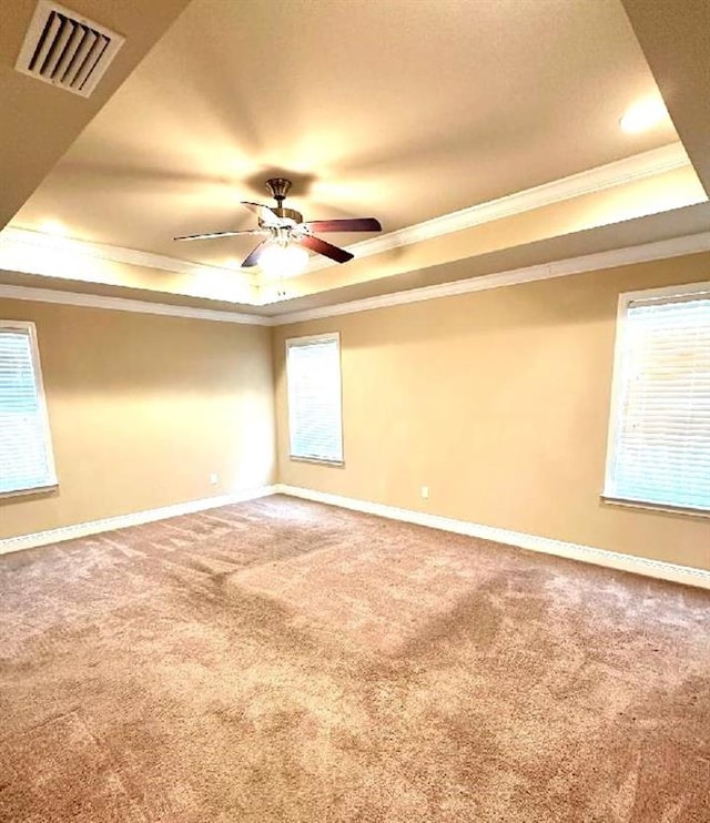 carpeted empty room featuring ceiling fan, a raised ceiling, and crown molding