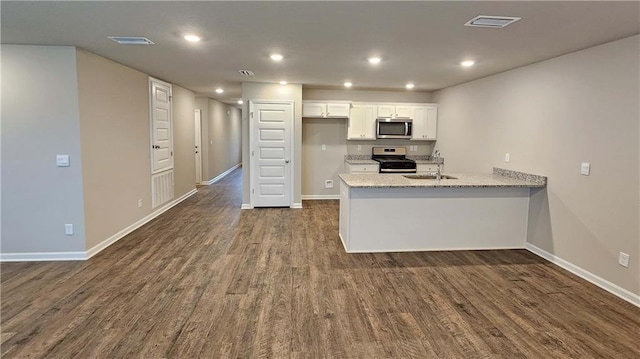 kitchen with dark hardwood / wood-style floors, light stone counters, white cabinetry, and appliances with stainless steel finishes