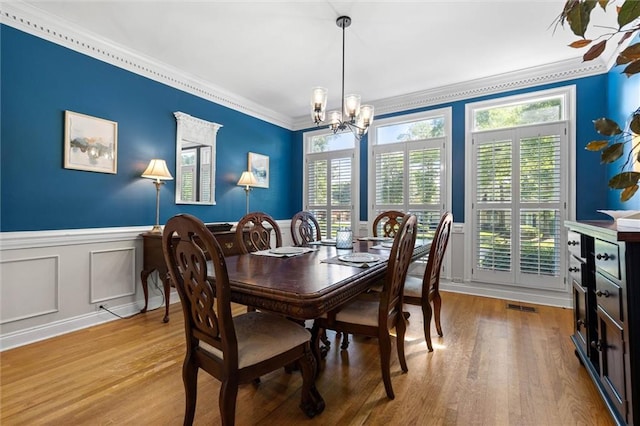 704 Providence Estates Dr E, Mobile, AL 36695 - dining room featuring ornamental molding, a chandelier, healthy amount of natural light, a wainscoted wall, and wood finished floors