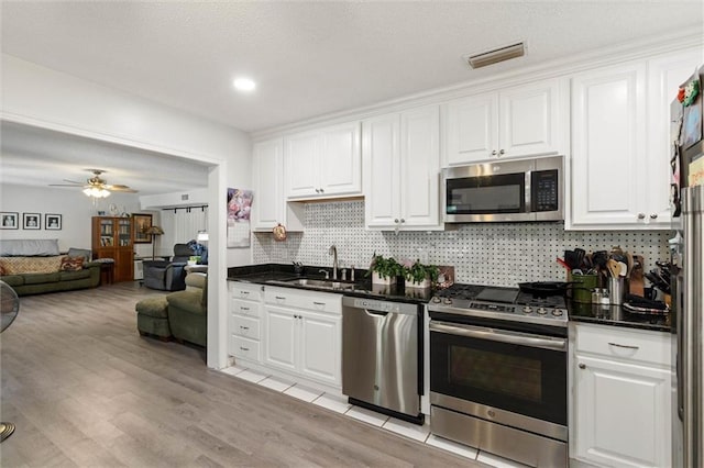 704 Providence Estates Dr E, Mobile, AL 36695 - kitchen featuring stainless steel appliances, a sink, white cabinets, decorative backsplash, and light wood-style flooring