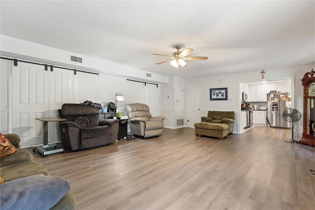 704 Providence Estates Dr E, Mobile, AL 36695 - living area featuring a barn door, ceiling fan, light wood-style floors, and a textured ceiling