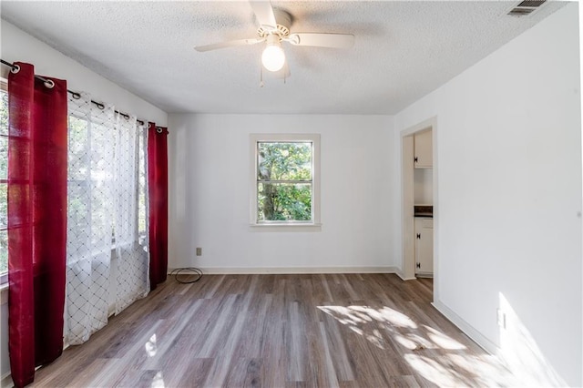 empty room with light hardwood / wood-style floors, ceiling fan, and a textured ceiling