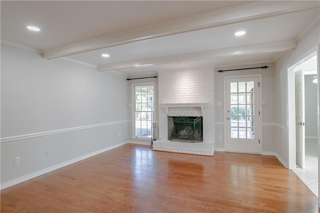 unfurnished living room with beamed ceiling, light hardwood / wood-style floors, a wealth of natural light, and a fireplace