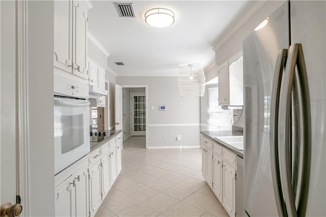 kitchen with oven, white cabinetry, black electric cooktop, light tile floors, and stainless steel refrigerator