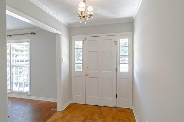 entrance foyer with plenty of natural light, a textured ceiling, a chandelier, and crown molding