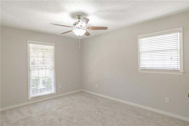 unfurnished room with ceiling fan, light colored carpet, and a textured ceiling