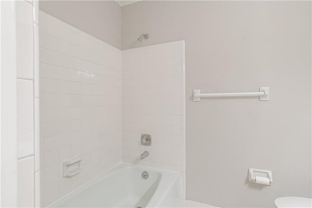 bathroom with toilet and tiled shower / bath