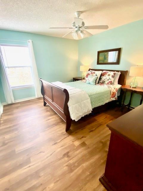 bedroom with hardwood / wood-style flooring, ceiling fan, and a textured ceiling