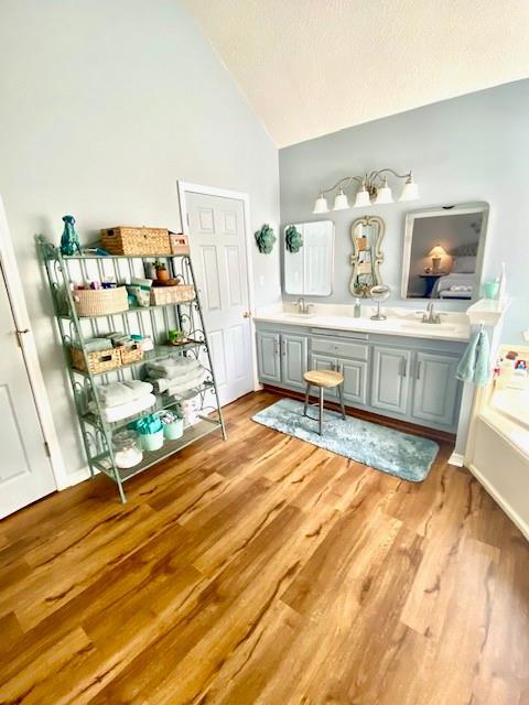 bathroom featuring wood-type flooring, a textured ceiling, vanity, and high vaulted ceiling