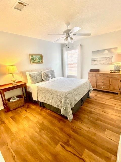 bedroom featuring ceiling fan, hardwood / wood-style floors, and a textured ceiling