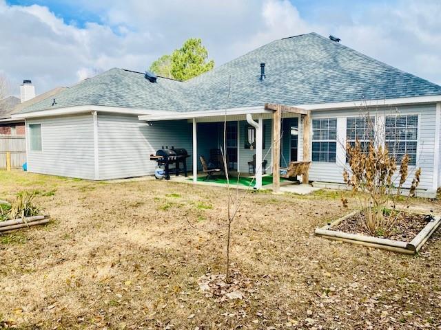 rear view of house with a patio and a yard