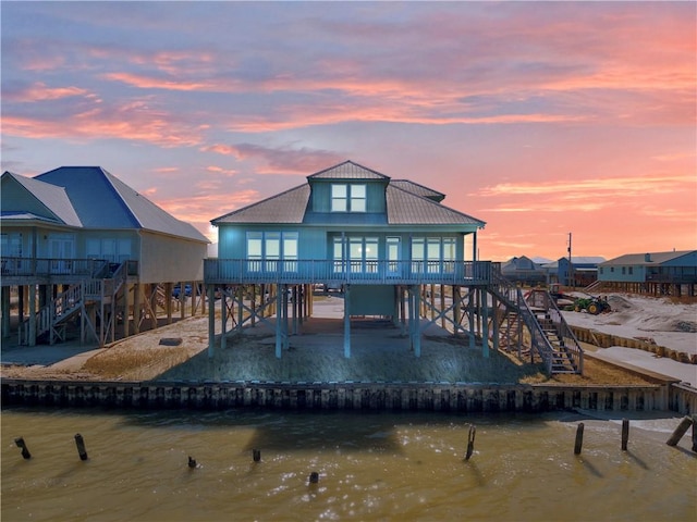 back house at dusk with a deck with water view