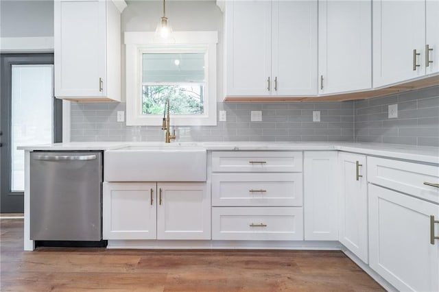 kitchen featuring light countertops, a sink, decorative backsplash, and stainless steel dishwasher