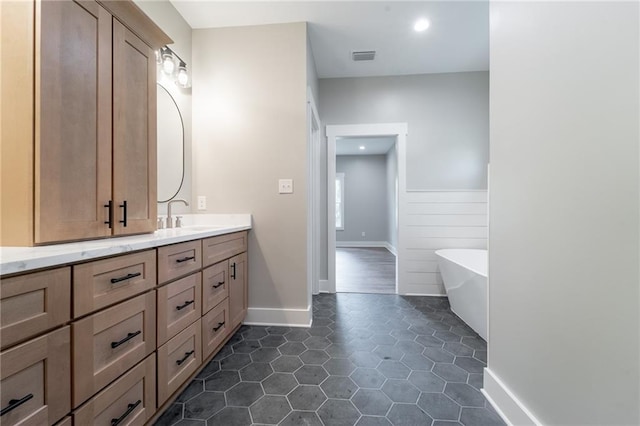 bathroom with visible vents, tile patterned flooring, wainscoting, a freestanding tub, and vanity