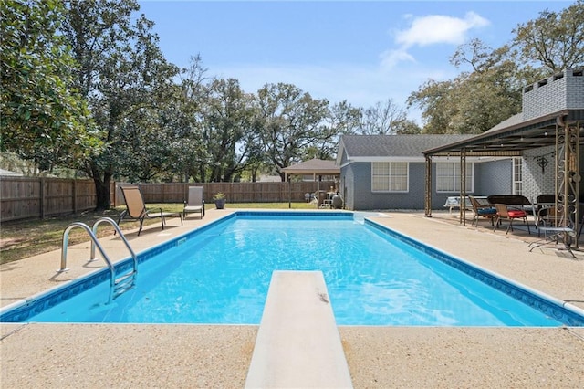 view of pool with a patio, a diving board, a fenced backyard, and a fenced in pool