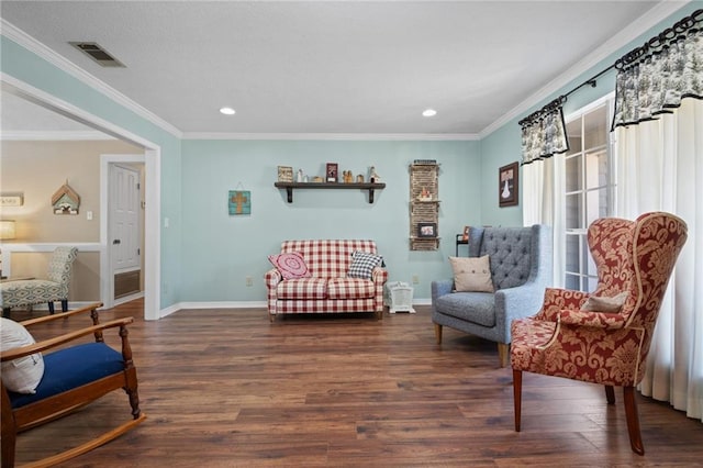 sitting room featuring visible vents, ornamental molding, baseboards, and wood finished floors