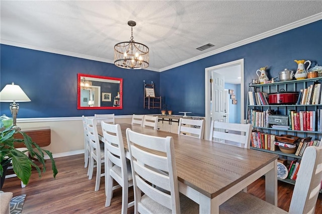 dining room with a chandelier, visible vents, ornamental molding, and wood finished floors