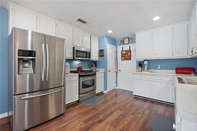 kitchen with dark wood finished floors, white cabinets, stainless steel appliances, and light countertops