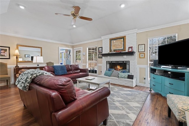 living area featuring hardwood / wood-style floors, ornamental molding, a fireplace, and vaulted ceiling