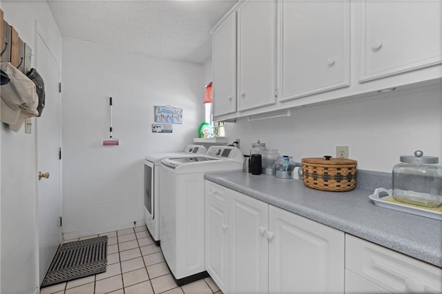 clothes washing area with cabinet space, light tile patterned floors, washing machine and dryer, and a textured ceiling