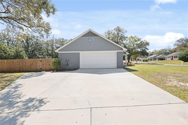 view of home's exterior with fence, driveway, an attached garage, a yard, and brick siding