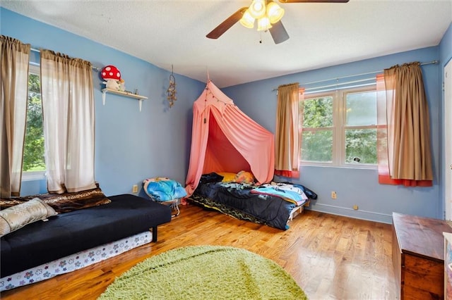 bedroom featuring multiple windows, wood-type flooring, and ceiling fan